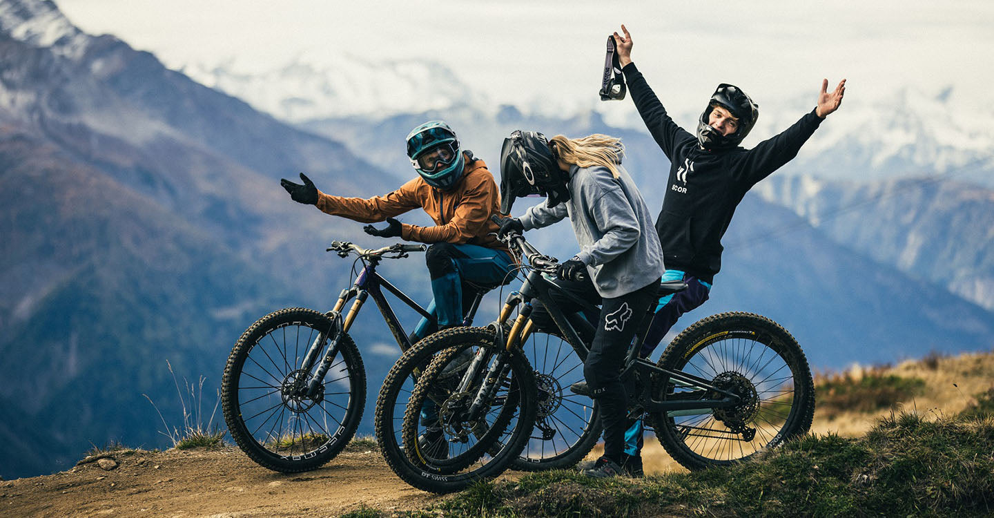 Joyful mountain bikers taking a playful break on a scenic overlook with expansive mountain views @ Bici.