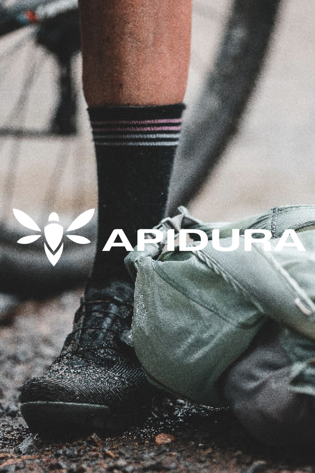 Adventurous cyclist tying a rugged Apidura bikepacking bag to a gravel bike @ Bici.