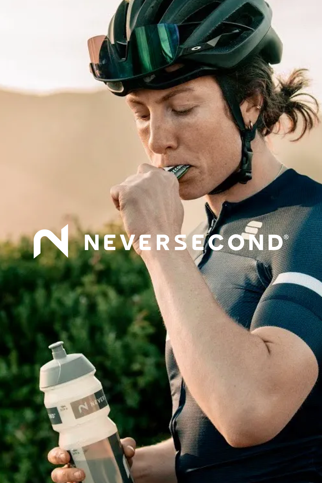 Determined cyclist in a helmet and sunglasses refueling with NEVERSECOND nutrition on a sunny day @ Bici.