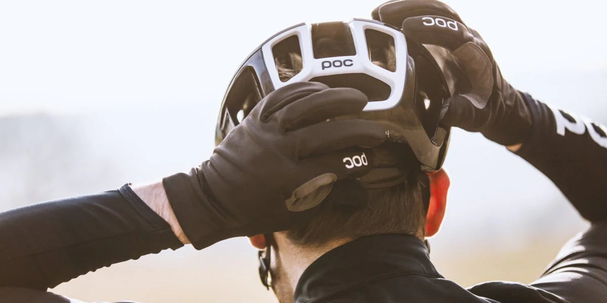 Rear view of a cyclist adjusting a black POC helmet, ready for a ride, with a focus on safety @ Bici.