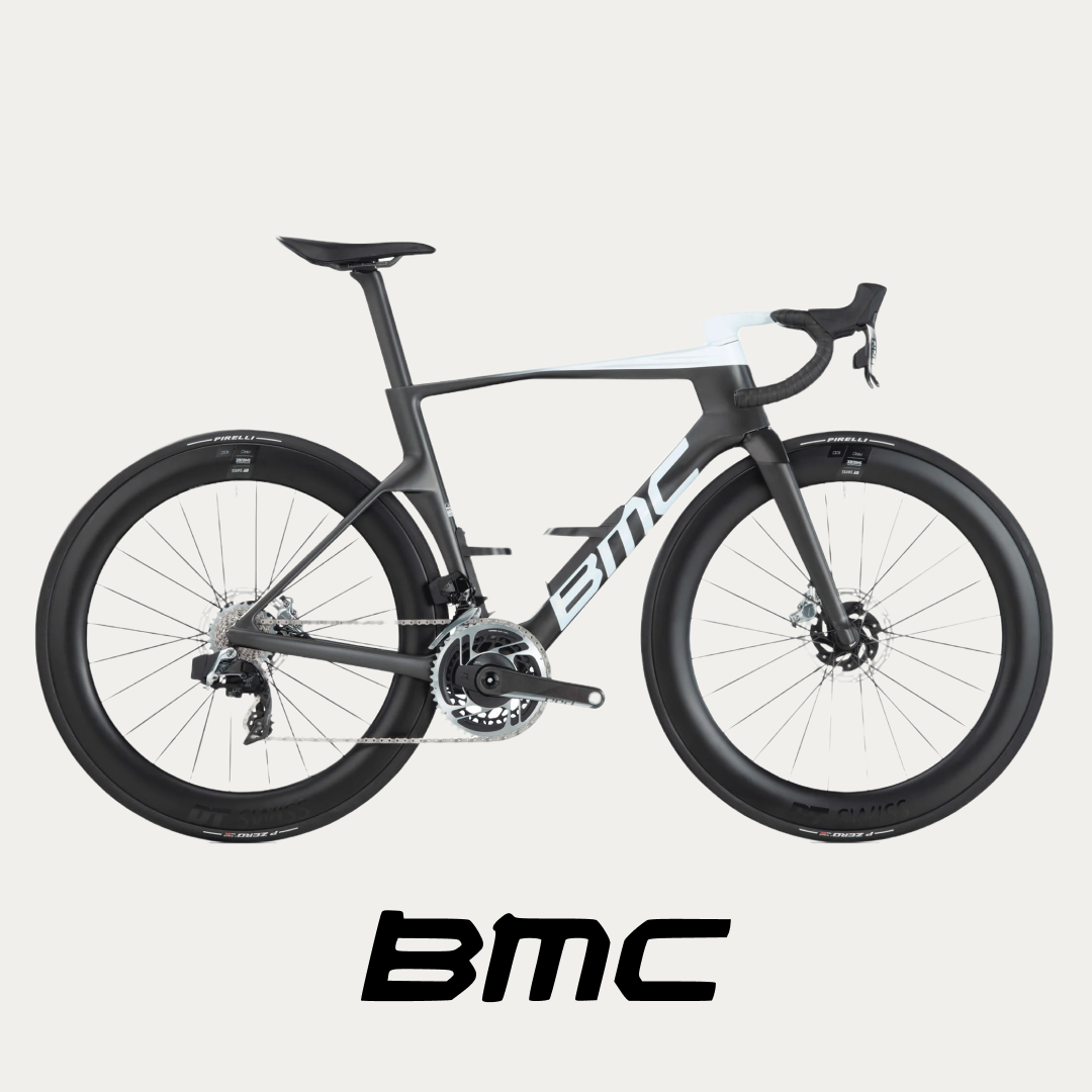 A sleek BMC road bike is displayed, featuring an aerodynamic frame, deep-section wheels, and a sophisticated grey color scheme @ Bici.