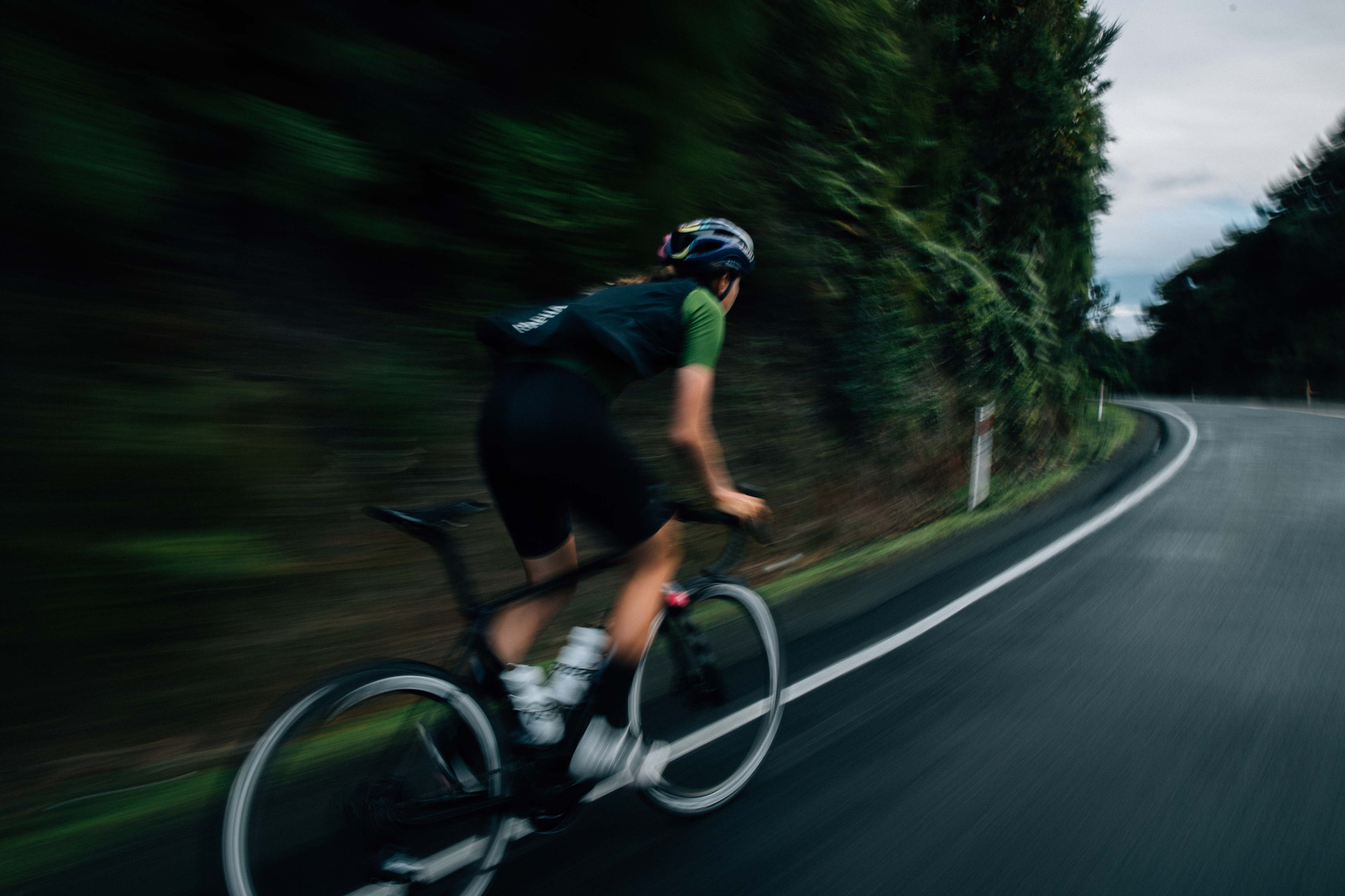 Blur of a cyclist speeding through a lush forested area, representing the dynamic service and expert bike care provided by Bici @ Bici.