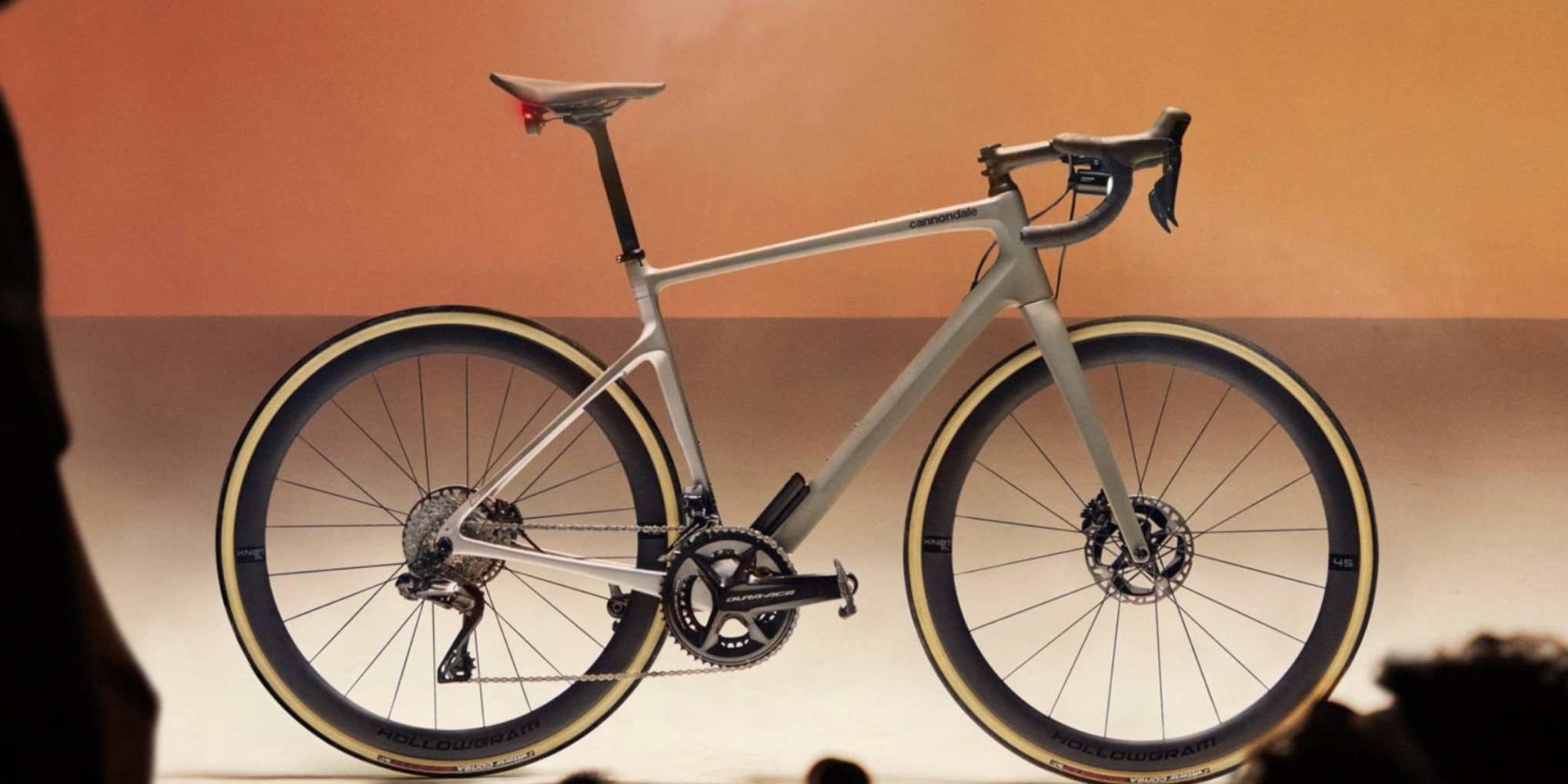Elegant road bike presented at an exhibit, featuring a modern, minimalist frame design set against a warm, neutral backdrop @ Bici.