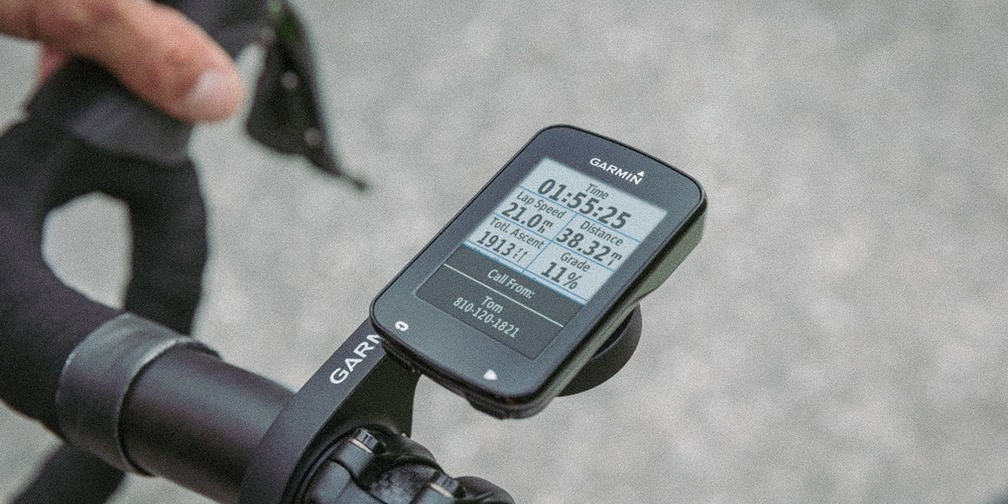 Cyclist’s hand on the handlebar with a Garmin bike computer displaying time, speed, distance, and grade data during a ride @ Bici.