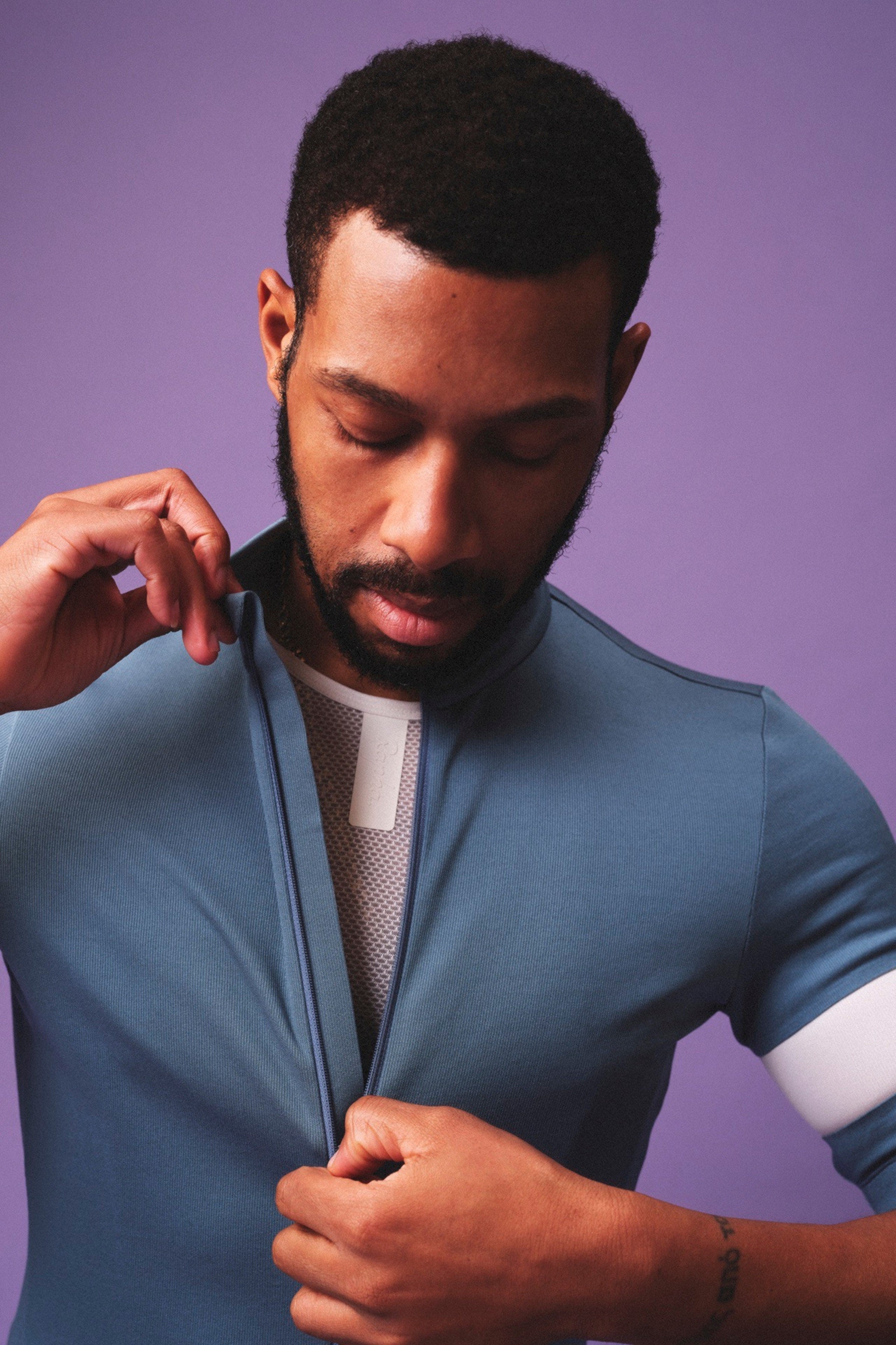Stylish cyclist zipping up a blue Rapha Core Collection jersey for a comfortable all-day ride @ Bici.